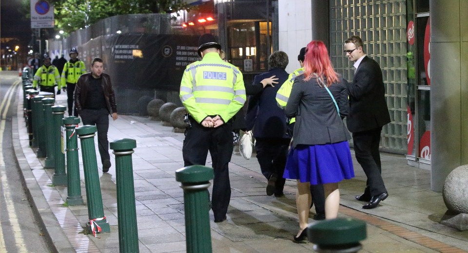  A reassuring hand is placed on the delegate's back as police and his friends guide him back to where he is staying