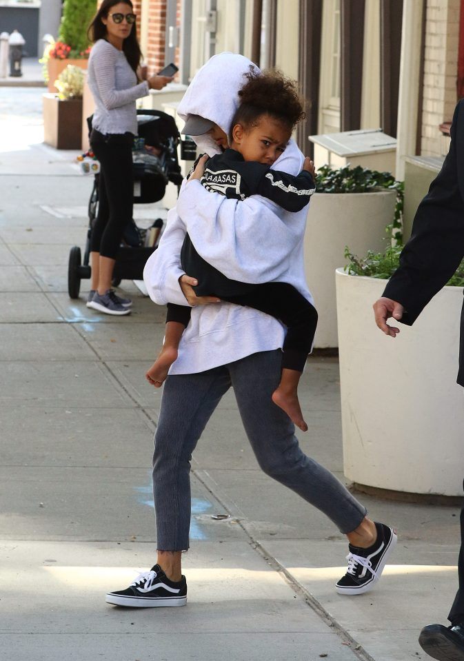  Kim covered her face as she emerged from her New York flat yesterday cradling daughter North West