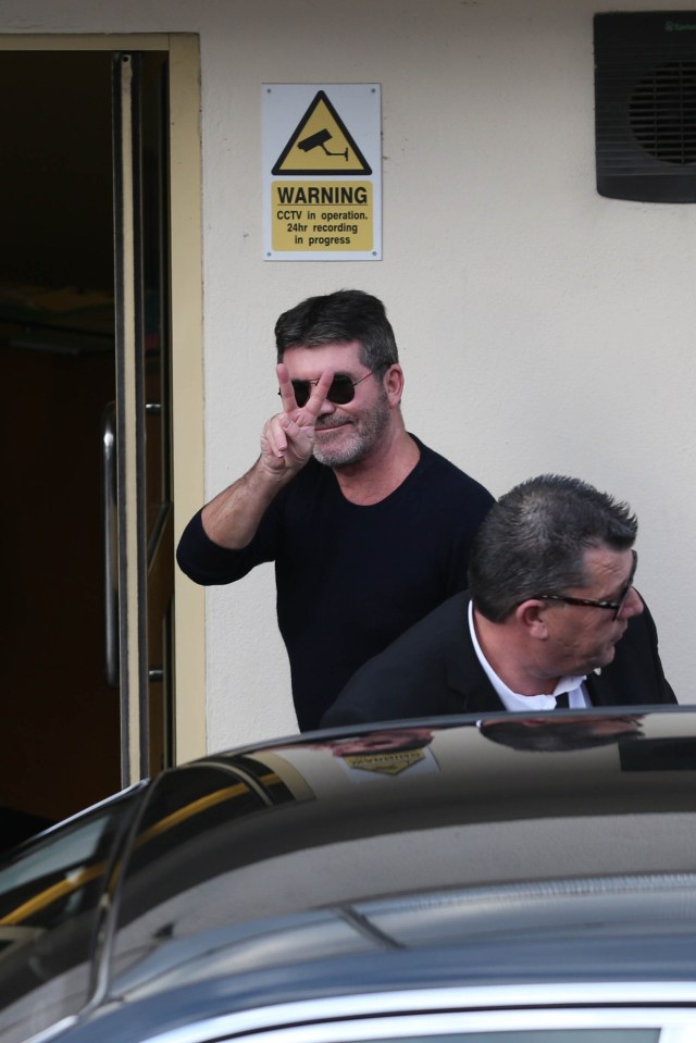 Despite appearing to be in the dog house, Simon gave a smile and the peace sign to the waiting cameras 