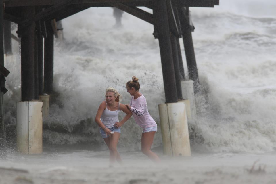 Two girls run for cover as they splash in the massive swells generated by the storm