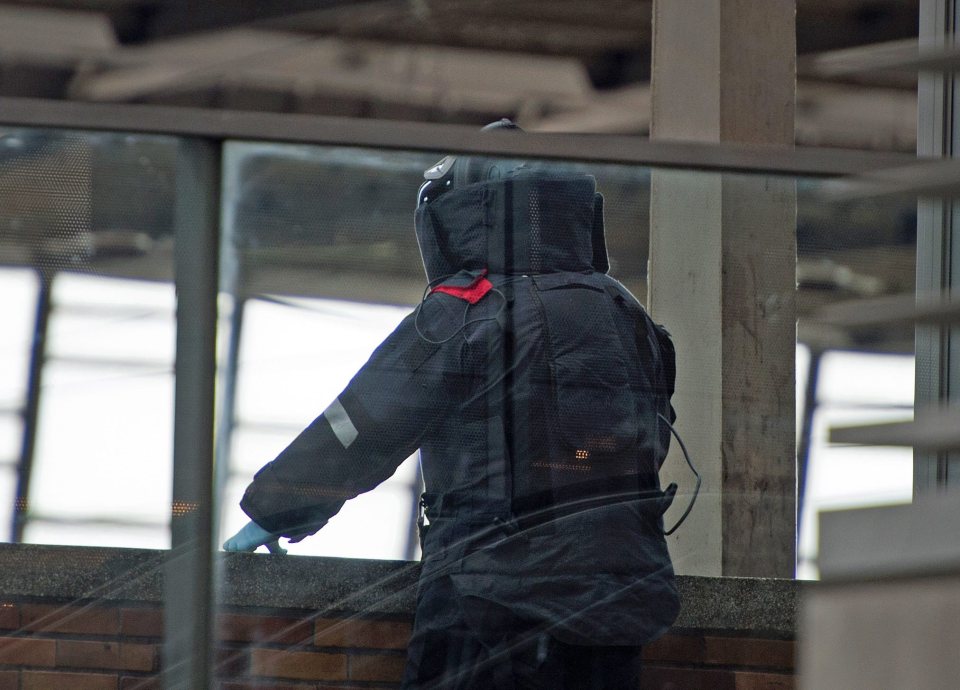  A police officer in protective clothing watches on as a remotely controlled bomb disposal robot lifts a suitcase on a platform Chemnitz Central Station