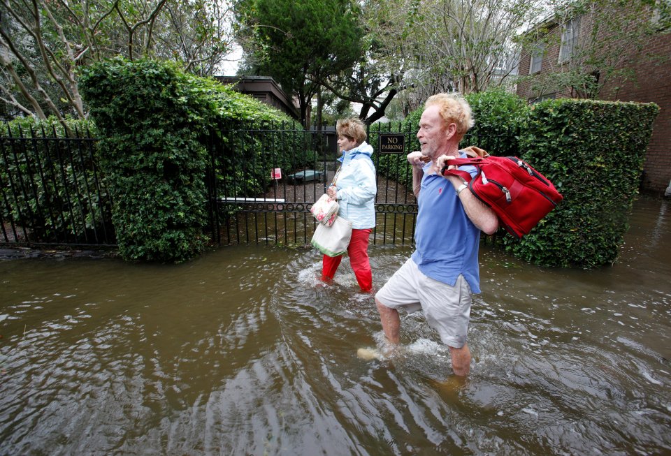  Residents of an upscale historic neighbourhood wade through flood waters as they return to their home after Hurricane Matthew hit Charleston