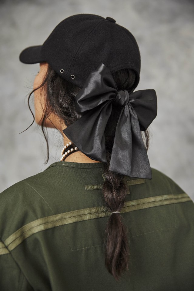  An edgy black cap features a giant silk bow at the back