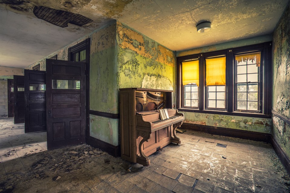  A piano lies abandoned, unplayed for decades as dust collects on its wooden frame