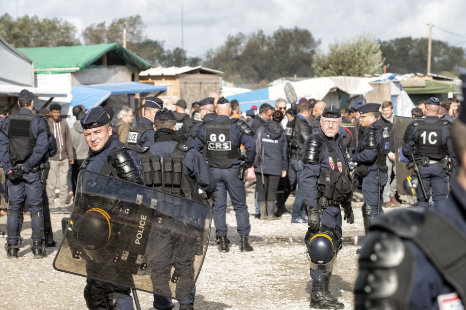  French police officers monitor the delivery of an eviction notice before the planned demolition of the Calais Jungle