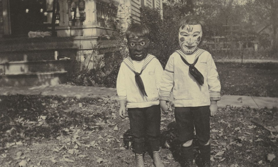  Two boys hold hands while wearing neck scarves and masks