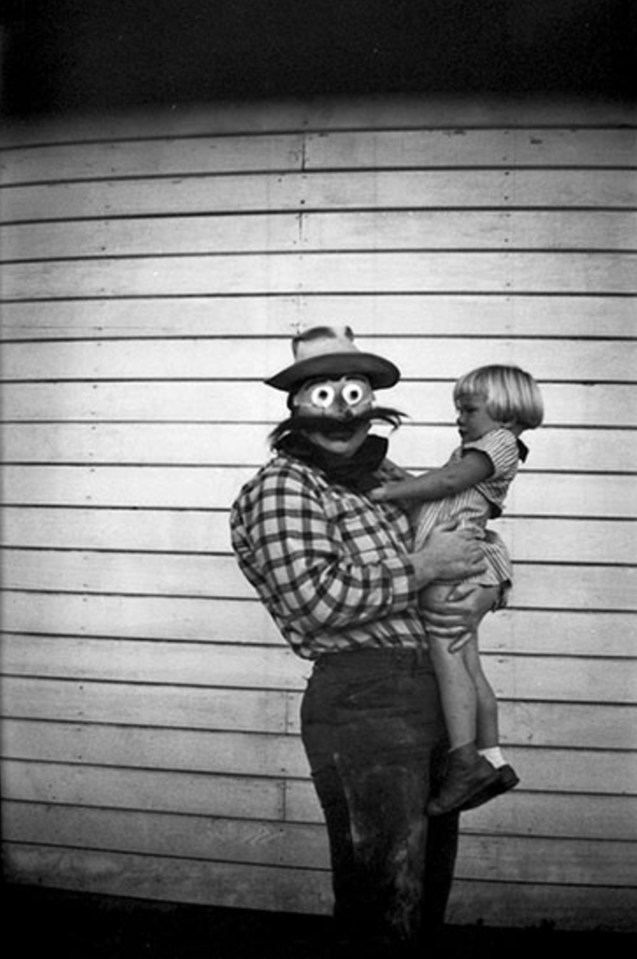  A girl looks in fear at the scary mask of the adult holding her