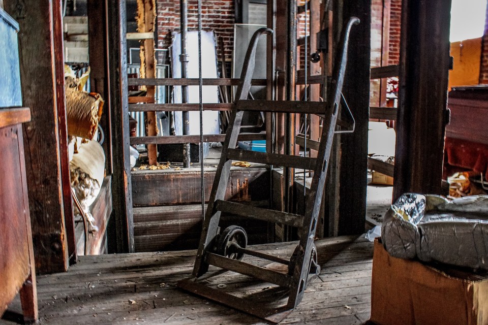  A wooden casket dolly sits in front of the elevator used to lower the caskets down to the first floor