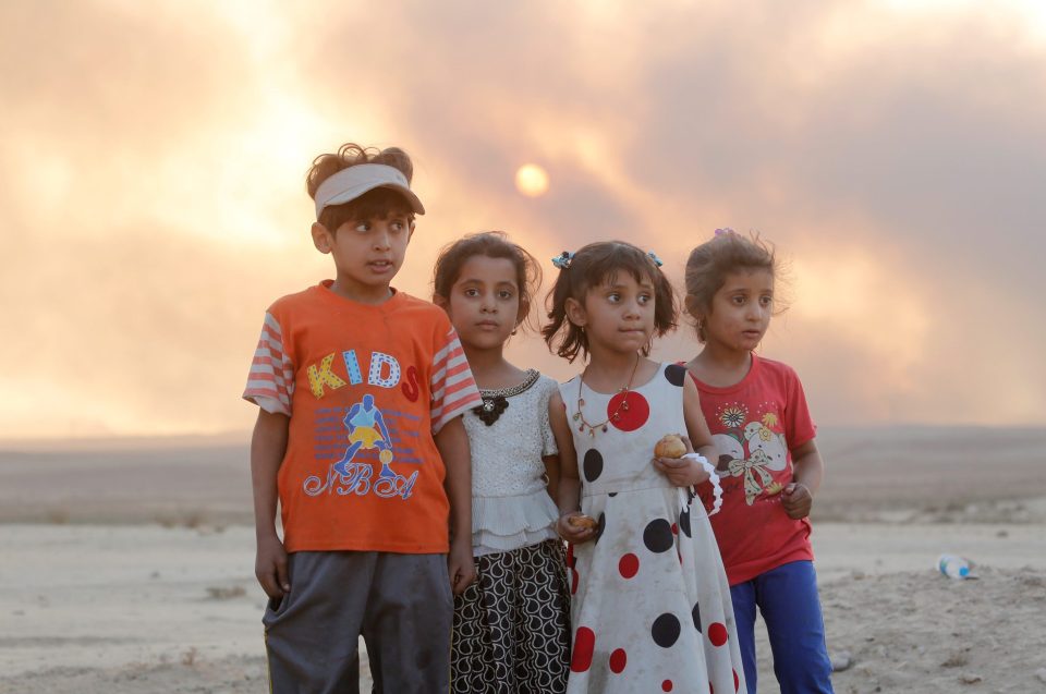  A group of Iraqi children look across their battle-worn home