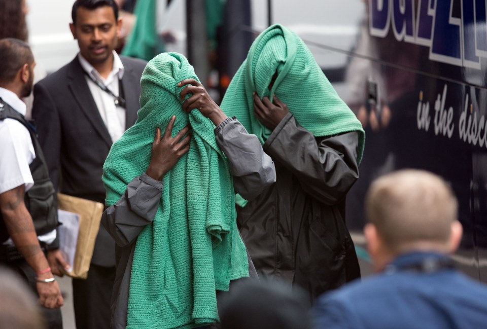  Calais migrant children cover their faces with blankets as they arrive at the immigration centre in Croydon