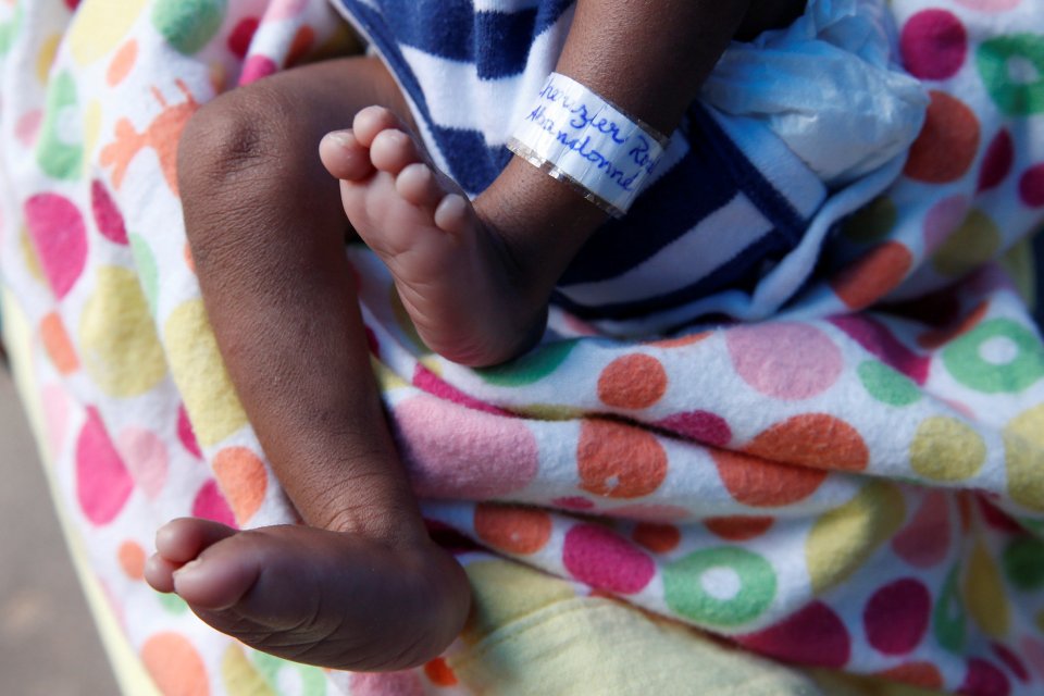 A strip of paper that says "abandoned" is seen on the leg of three-month-old Micah