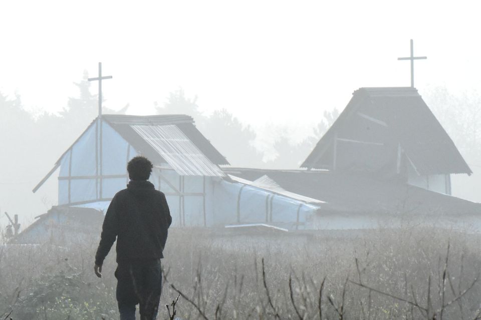  A migrant walks past a makeshift church in the camp which is due to be demolished tomorrow