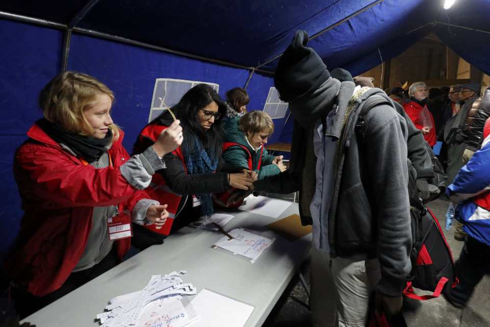  A migrant queues to receive a bracelet before being transferred to a reception centre