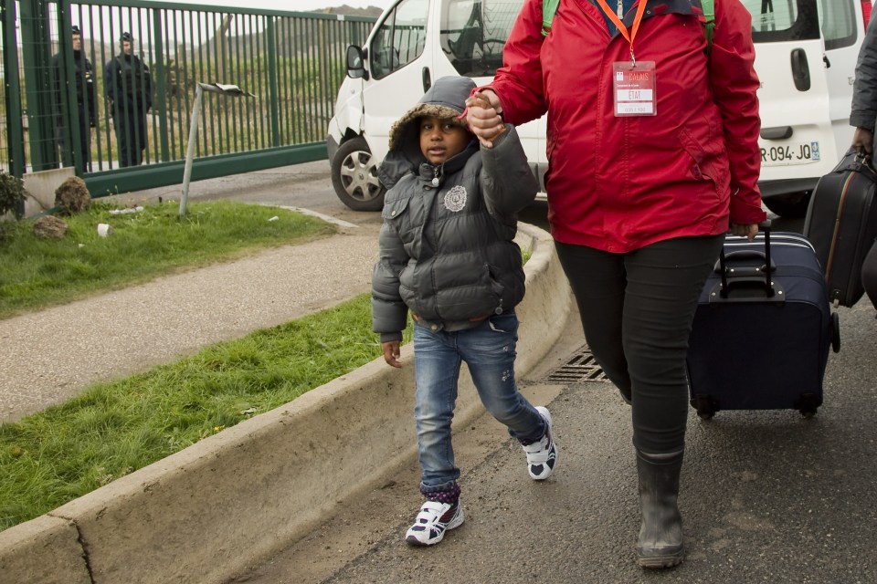  A child is led away from the camp after migrants were told to leave this morning