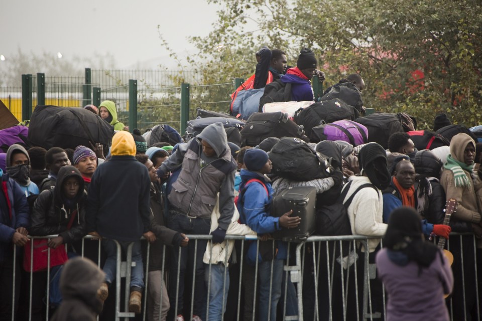  Refugees with their luggage wait to leave the notorious shantytown