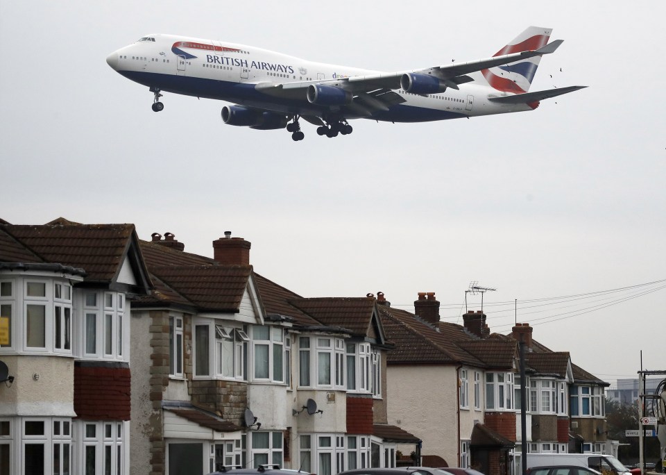 A plane approaches landing over the rooftops of nearby houses at Heathrow Airport