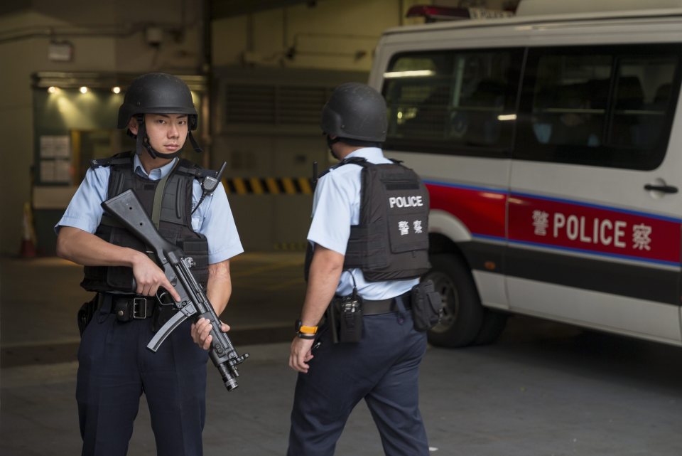  Police stand guard prior to the departure of a van carrying Rurik Jutting