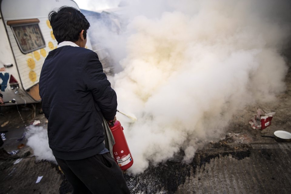  An Afghan migrant extinguishes a fire