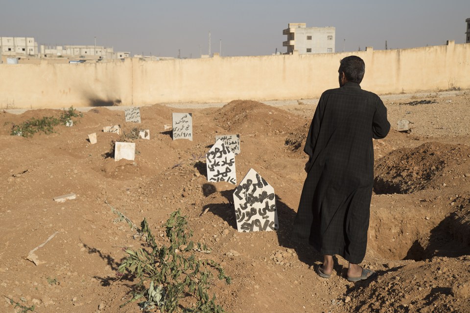  A family member stands next to the graves of three children who were killed when an explosive device planted by Islamic State group in a school detonated