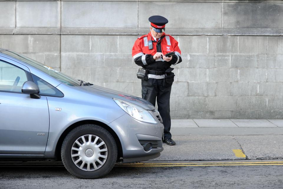 A traffic warden issues a parking ticket to an illegally parked car.