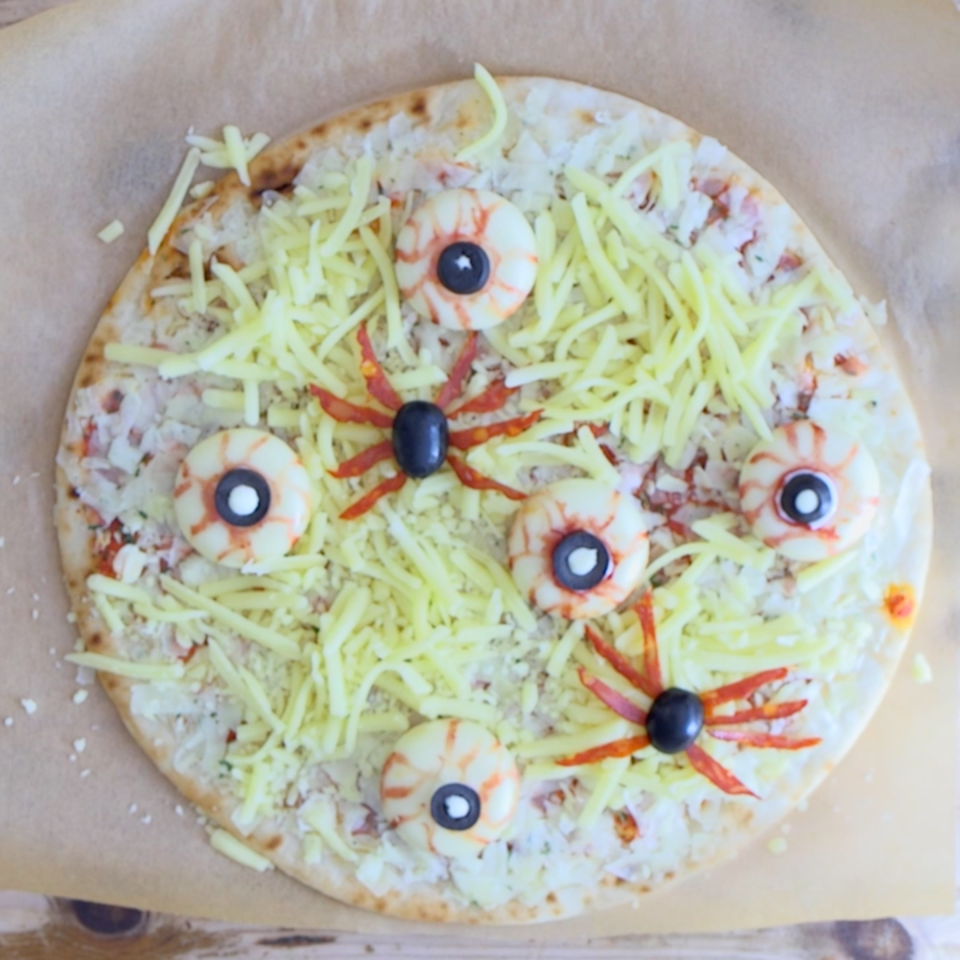  Add the cheesy eyes and place the chorizo and olives in the shape of spiders