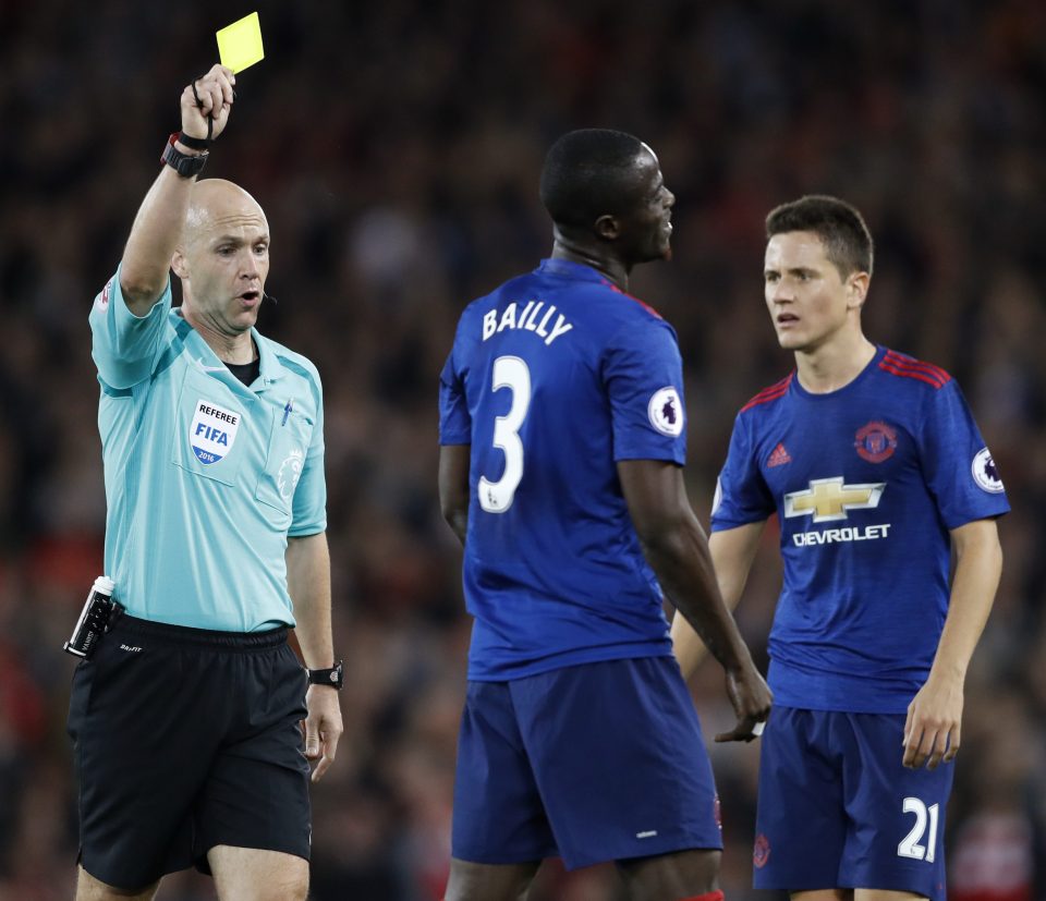  Utd defender Eric Bailly picks up a yellow card from ref Anthony Taylor at Anfield