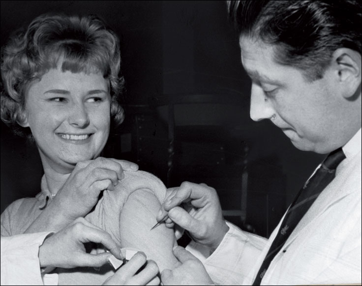  This woman is being vaccinated, with a simple lancet called a bifurcated needle, as part of a mass programme of vaccination against smallpox.