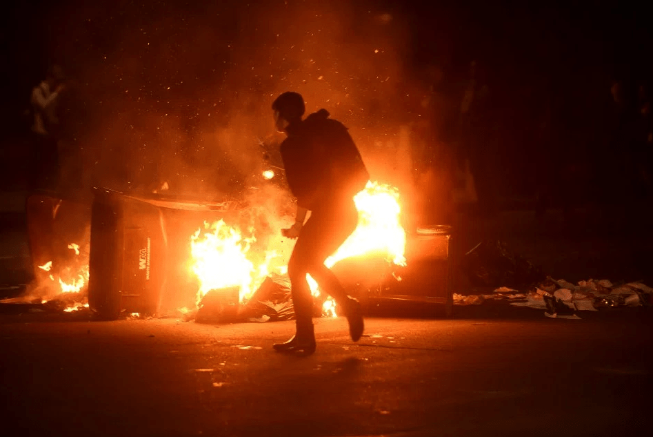  A woman passes burning garbage during a demonstration in Oakland, California