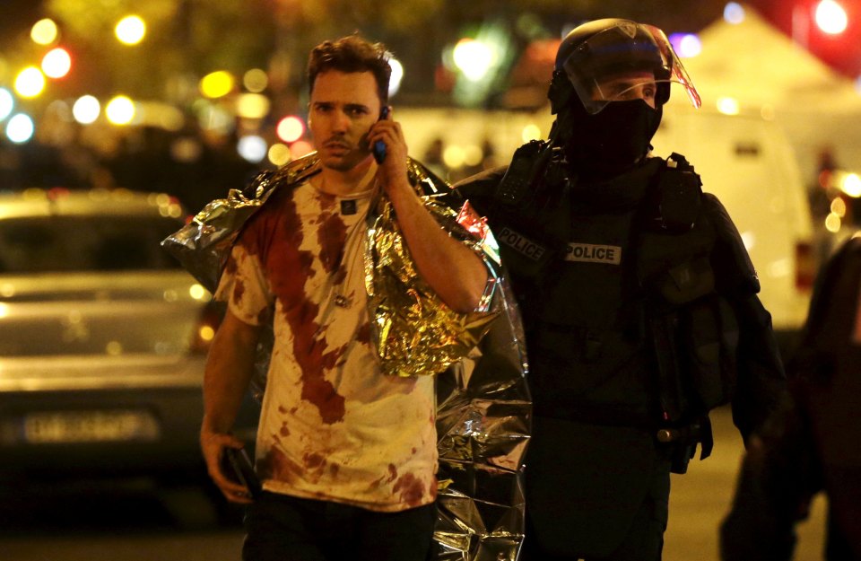  A French policeman assists a blood-covered victim near the Bataclan concert hall following the attacks