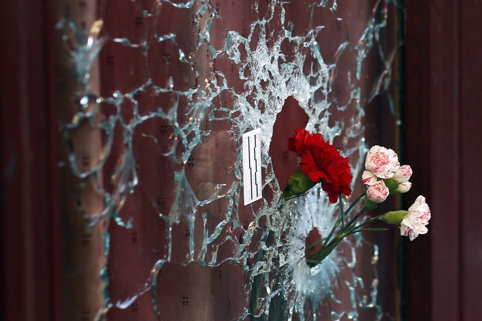  Flowers are set in a window shattered by a bullet at the Carillon cafe in Paris