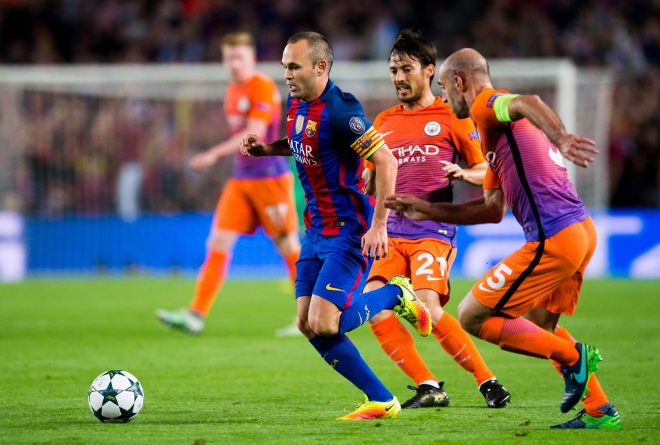 Andres Iniesta (L) of FC Barcelona runs with the ball next to David Silva