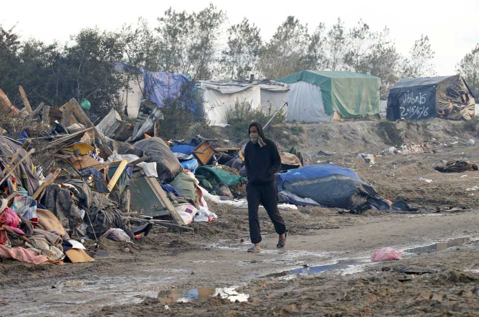  A man walks past debris from makeshift shelters while the Jungle was destroyed last week