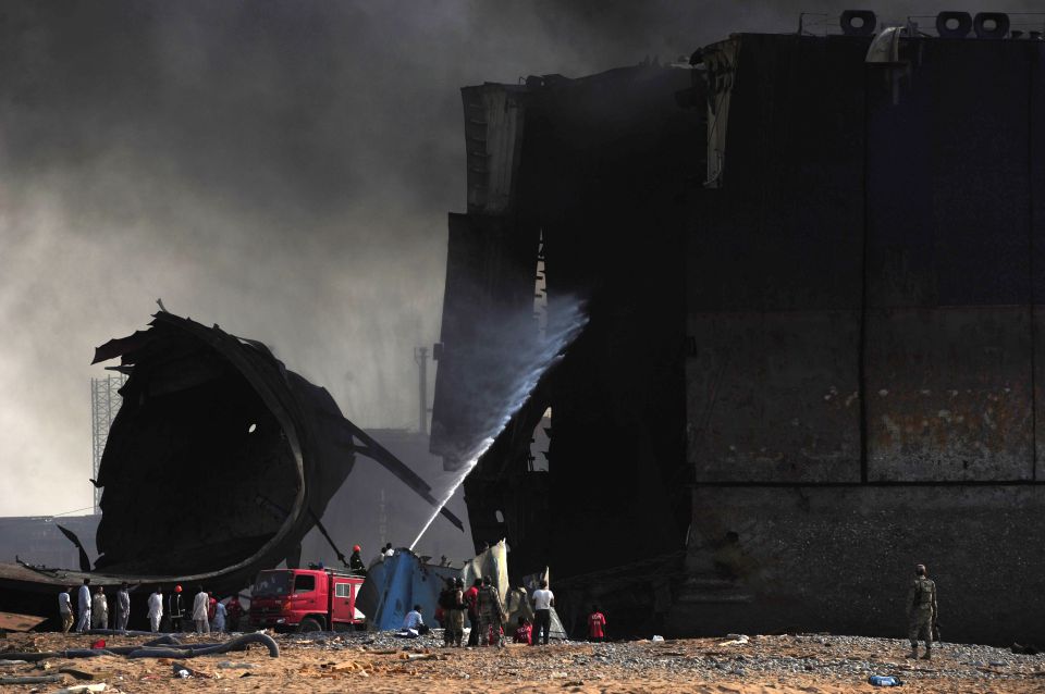 Pakistani firefighters use a hose as they attempt to extinguish a fire on the burnt ship 