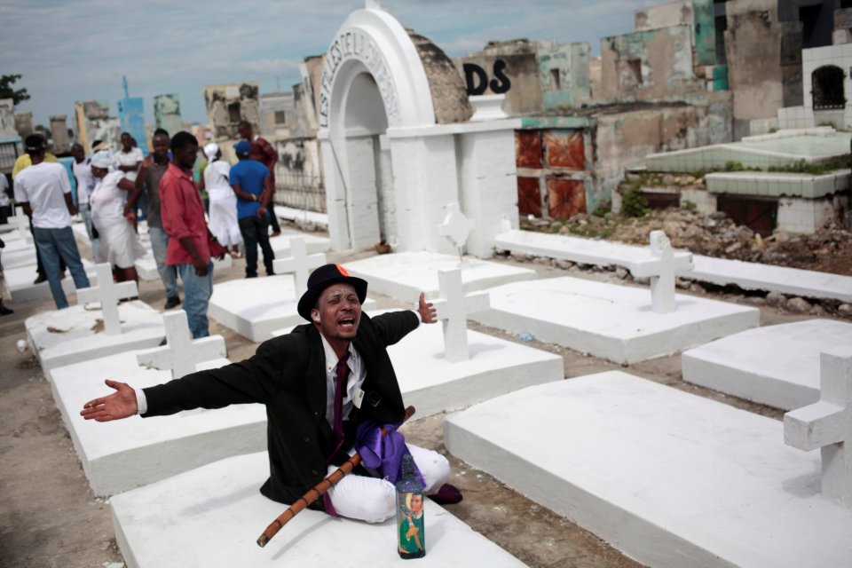  A man dressed as a "Gede", or spirit of voodoo, greets people as they enter the cemetery