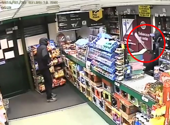  One of the thugs holds the knife in front of the terrified worker