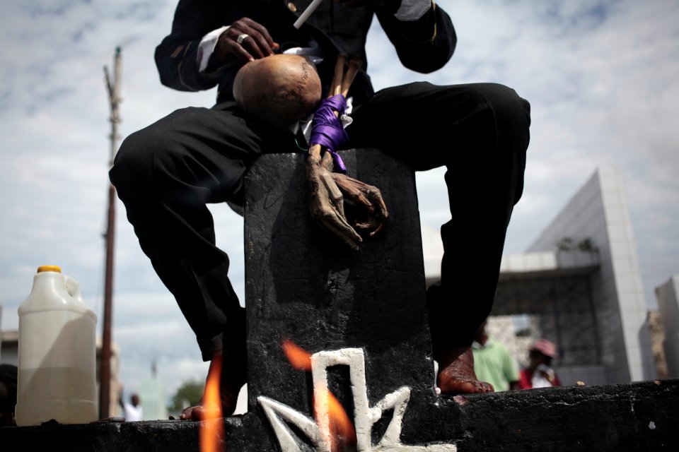  A voodoo believer is perched on the cross of Baron Samedi in Port-au-Prince