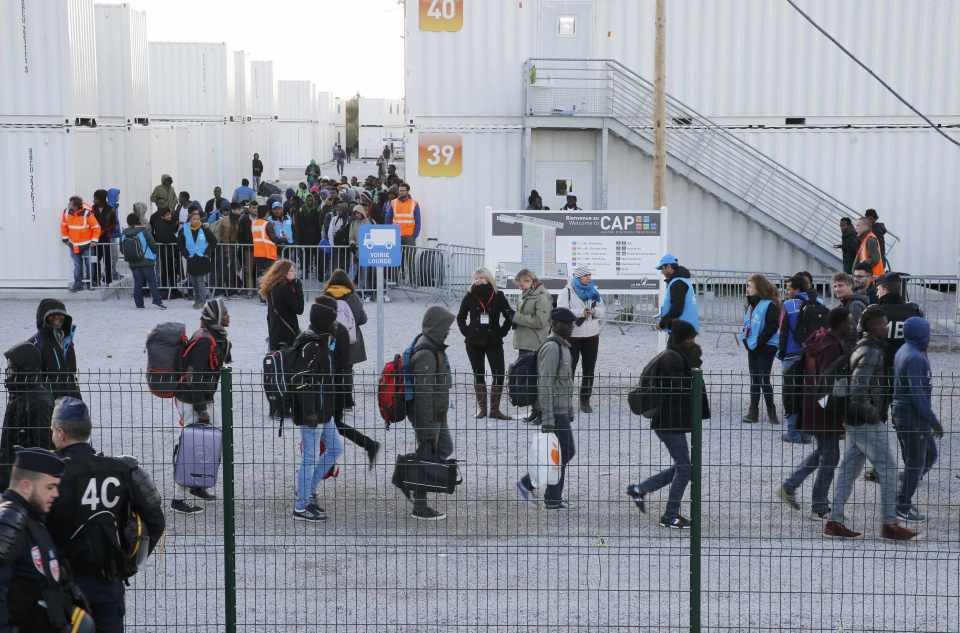  Migrants leave converted shipping containers, where they have been housed