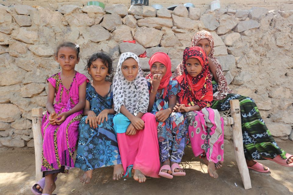 Yemeni girls sit on a wooden bench on Se