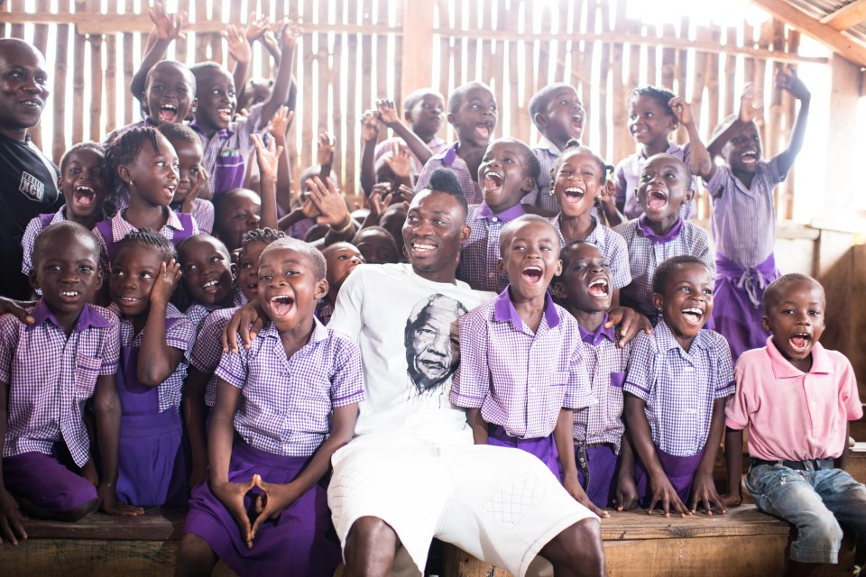  Christian Atsu sits with children back home in Ghana where he helps with charity work for orphans