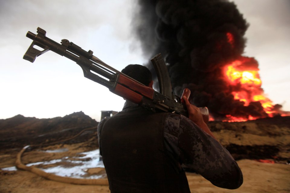  A member of the Iraqi security forces looks at fire from oil wells set ablaze by Islamic State militants