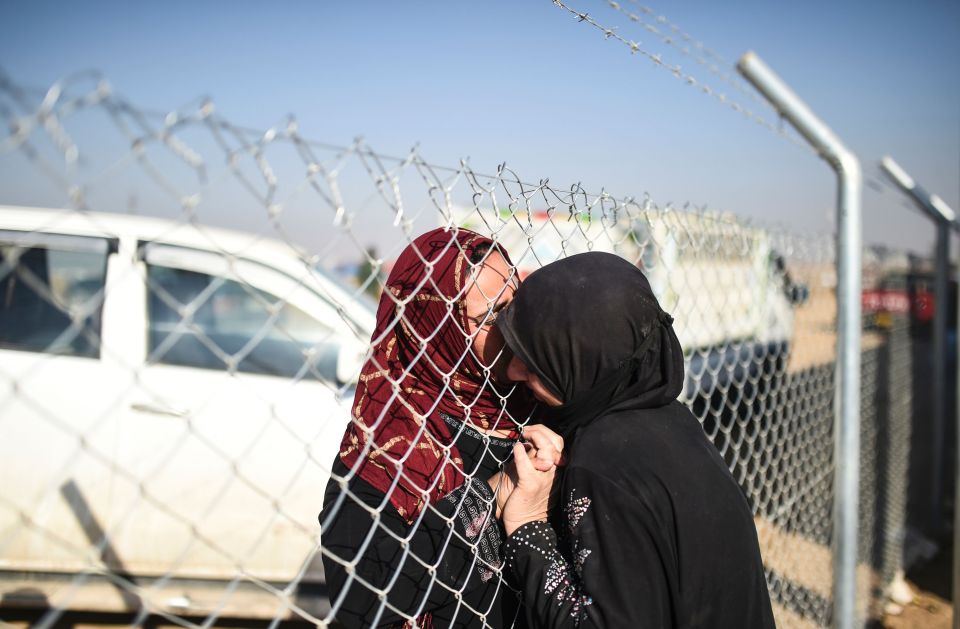  Iraqi woman, left, greets a relative from her refugee camp outside Mosul today