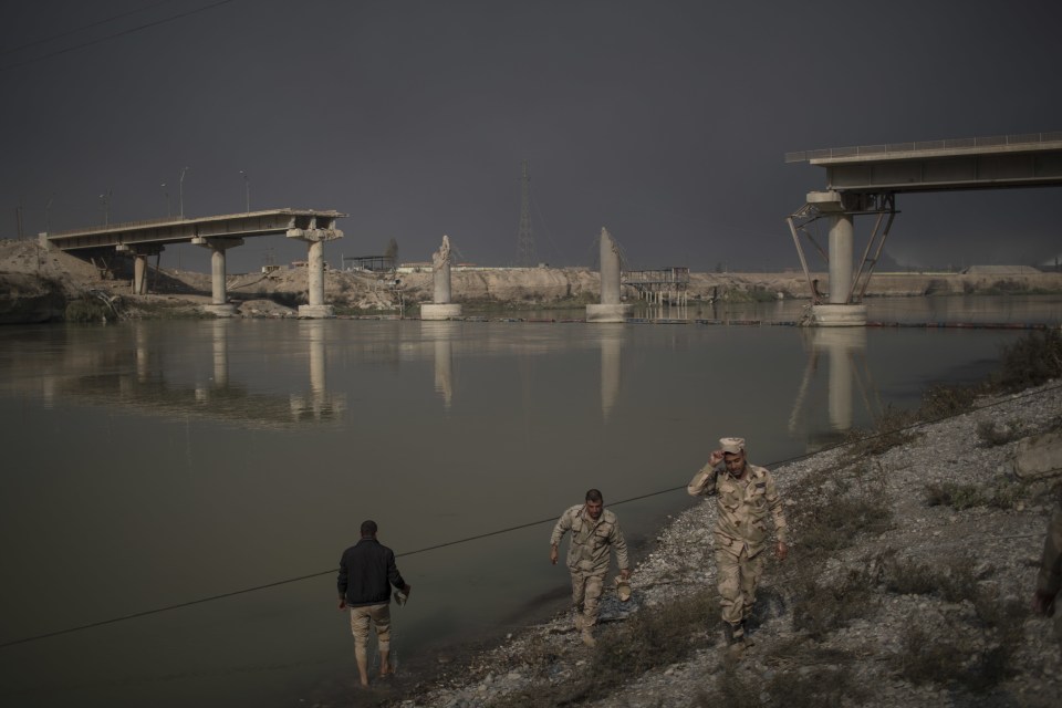  Iraqi soldiers near a bridge destroyed by an airstrike in Qayara today