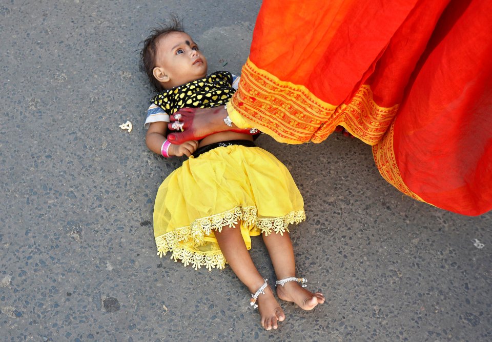  A Hindu woman steps over a child in a ritual seeking blessings from the Sun god during the religious festival of Chhat Puja in Kolkata, India