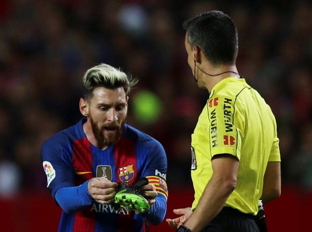 Barcelona striker Lionel Messi attempts to show the referee his snapped bootlace