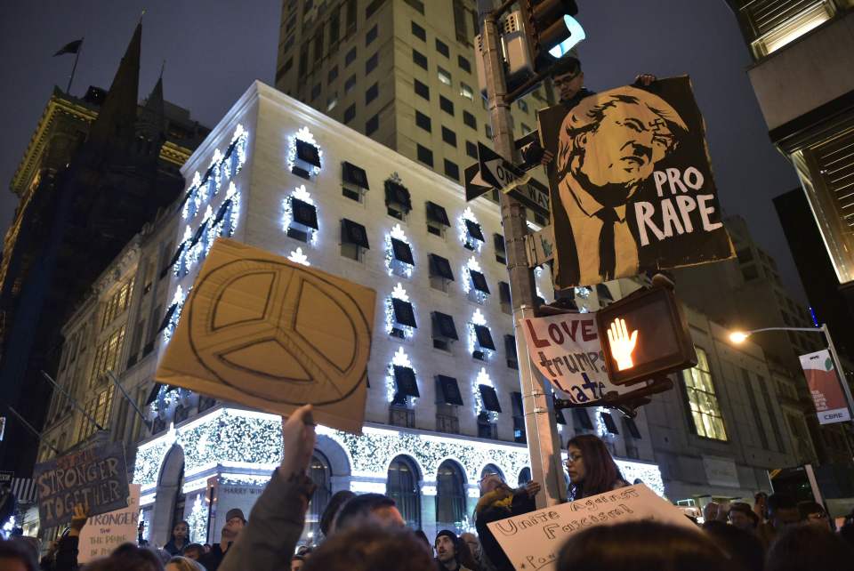  Protesters hold placards showing Donald dressed as Hitler on 5th Avenue across from Trump Tower