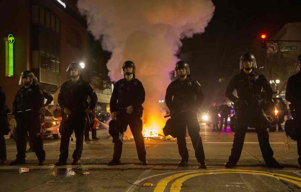 Police hold a skirmish line as a trash f