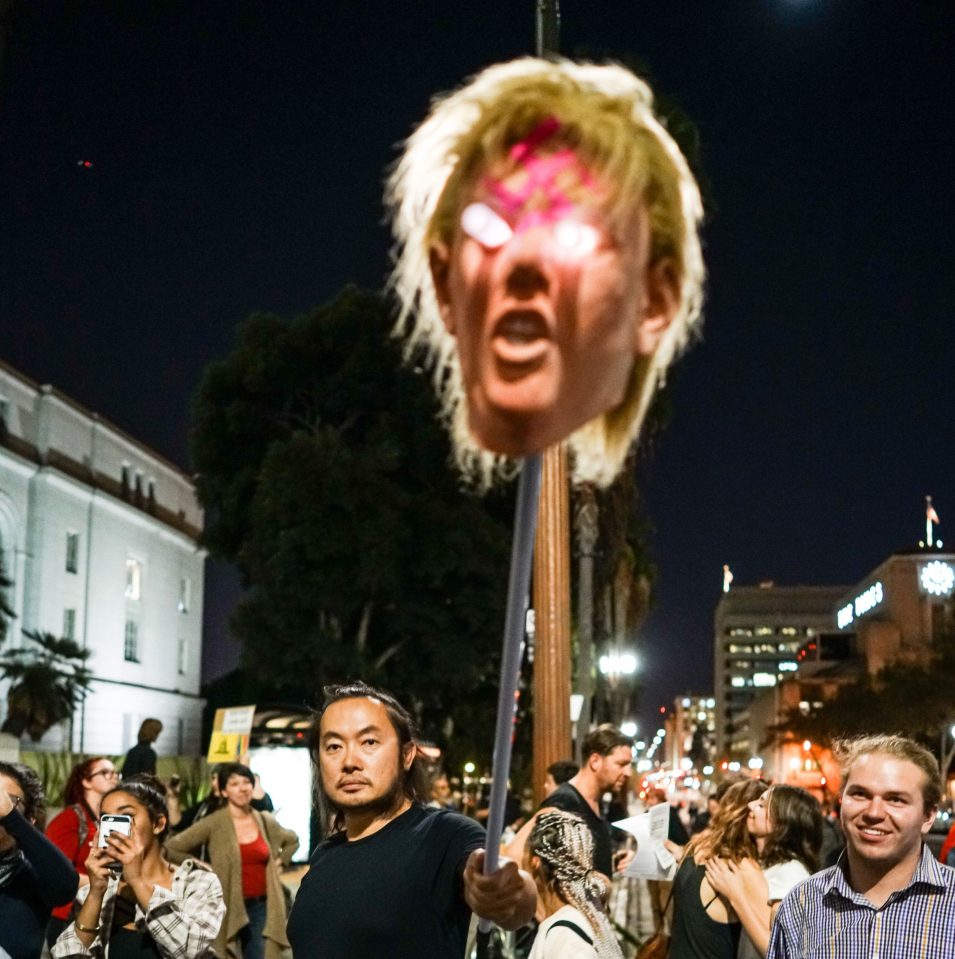  A sinister fake head resembling Donald Trump is wielded by a protestor