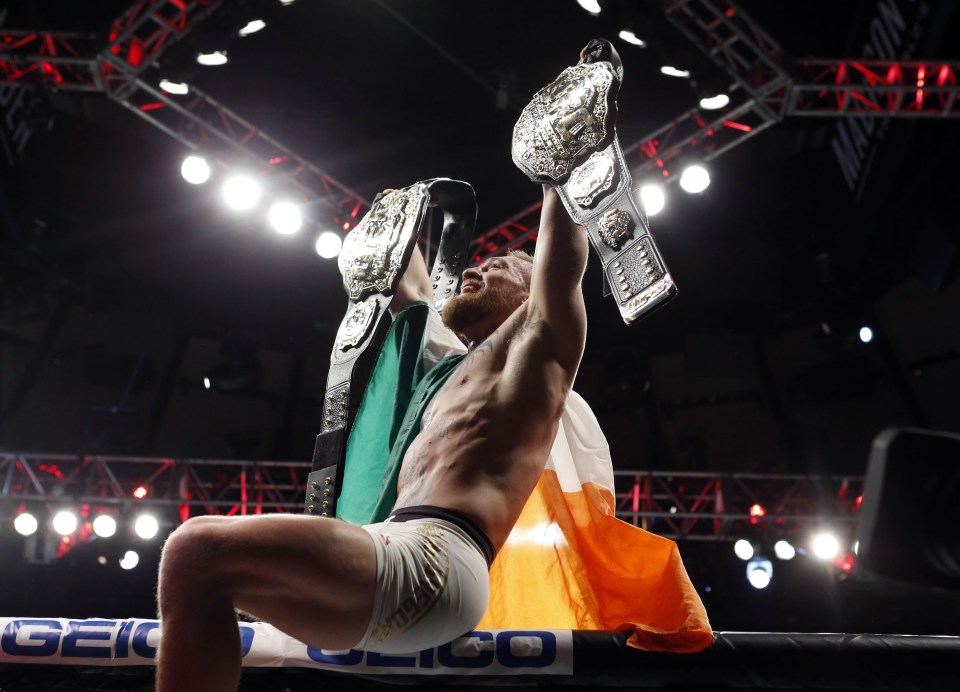  Conor McGregor celebrates with his two championship belts after defeating Eddie Alvarez (red gloves) in their lightweight title bout during UFC 205