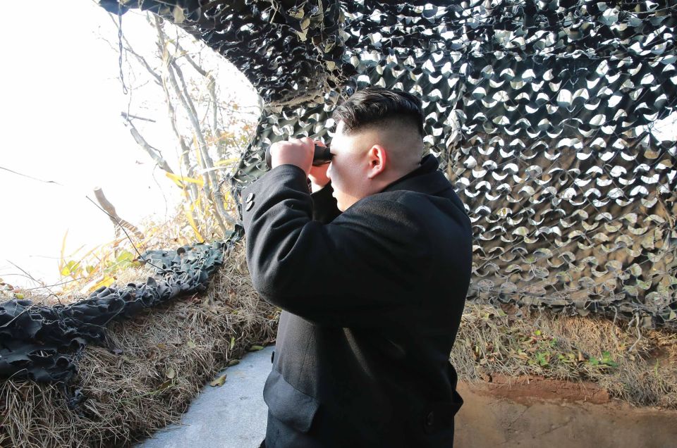  The leader looks out to sea and surveys the landscape as he is briefed on military exercises