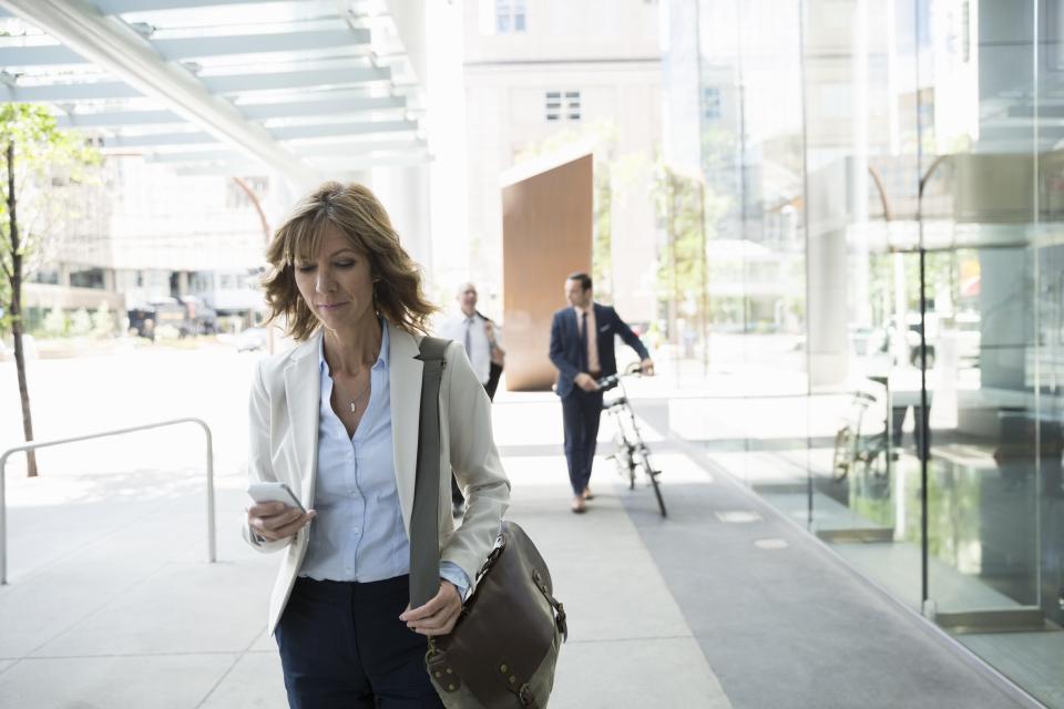 Businesswoman texting with cell phone on urban sidewalk